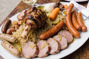 Wein zum Essen Choucroute Garnie mit Wurst, Fleisch, Sauerkraut & Riesling d’Alsace auf französischer Landtafel