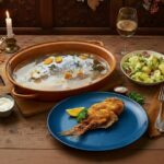 Wine with your meal - Franconian carp (blue & baked) with side dishes on a wooden table and Pinot Blanc by the glass