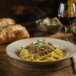 Wine with food - lentil and mushroom Bolognese with herbs and pecorino on a rustic wooden table with a Chianti glass