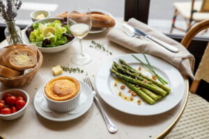 Green asparagus with goat's cheese soufflé and walnut vinaigrette on a white plate, Sancerre white wine glass, Parisian bistro setting