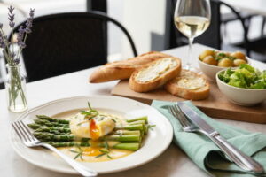 Green asparagus with poached egg and Béarnaise sauce on a plate, with a glass of Côtes du Rhône Blanc next to it