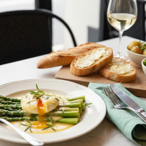 Green asparagus with poached egg and Béarnaise sauce on a plate, with a glass of Côtes du Rhône Blanc next to it