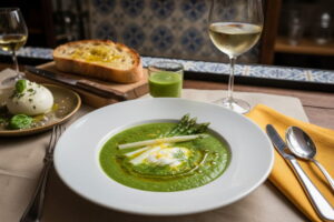 Cold asparagus gazpacho with green asparagus and yogurt in a deep plate, with a glass of Rueda DO Verdejo next to it