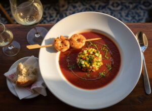 Gazpacho Andaluz with prawn skewer in a matte soup plate, manzanilla glass, Spanish tapas bar setting